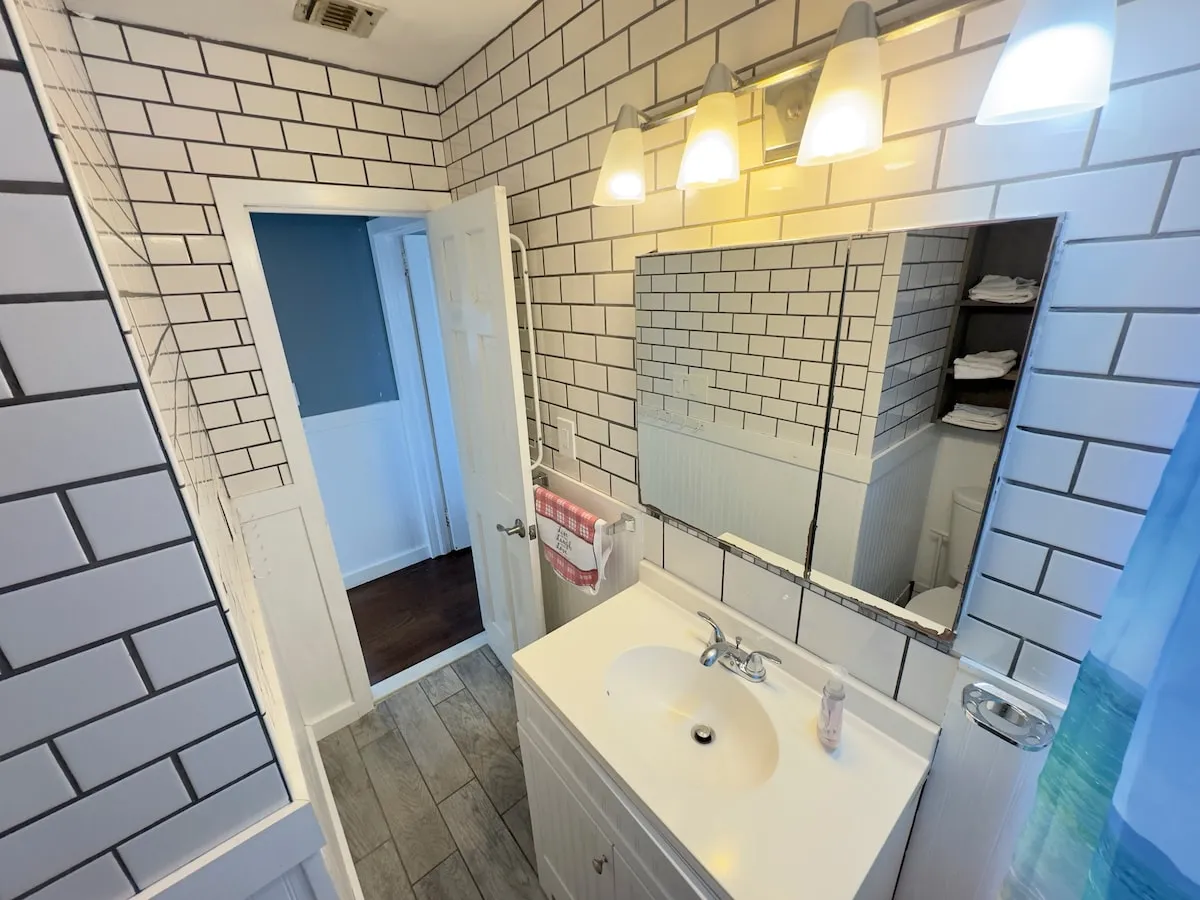 The remodeled bathroom with white subway tile and vanity