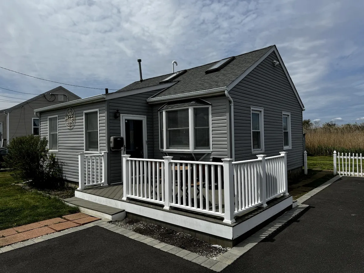 The gray-shingled ranch house with its white porch railing