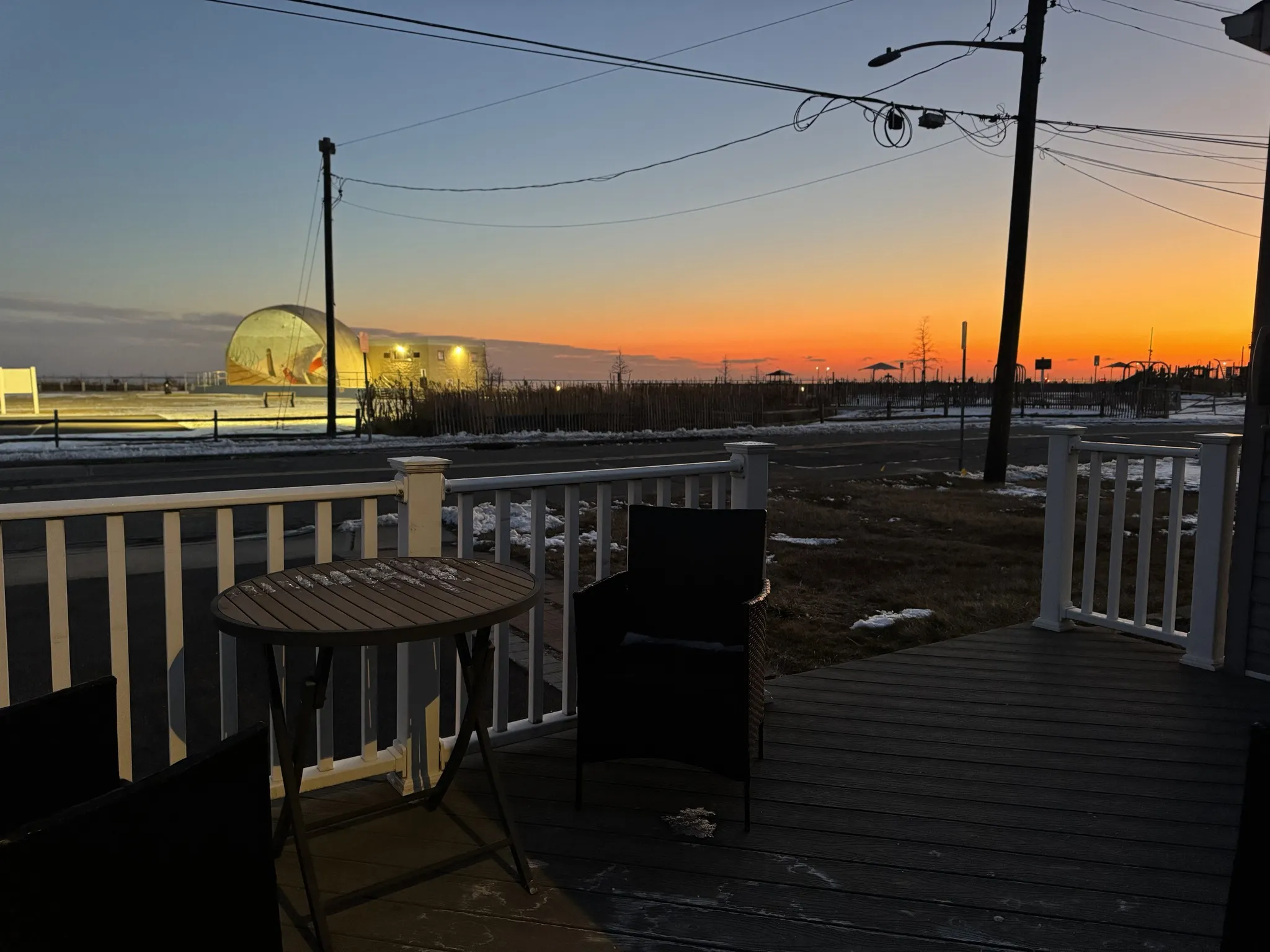 The patio at dusk, looking out at the Shorefront Band Shell lit by the sunset
